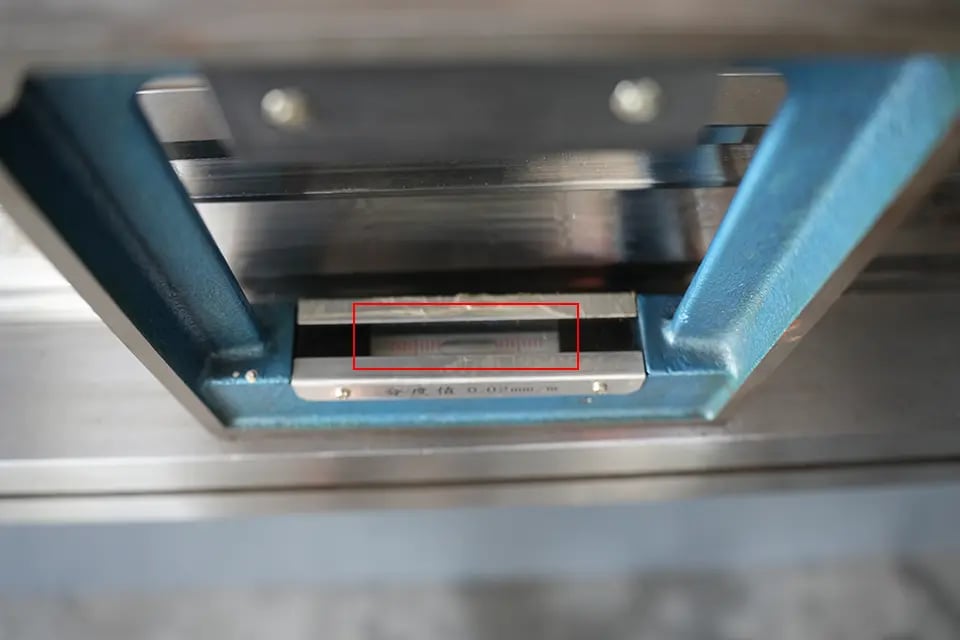 Uma régua de nível deve ser colocada horizontalmente no meio da bancada da prensa dobradeira.